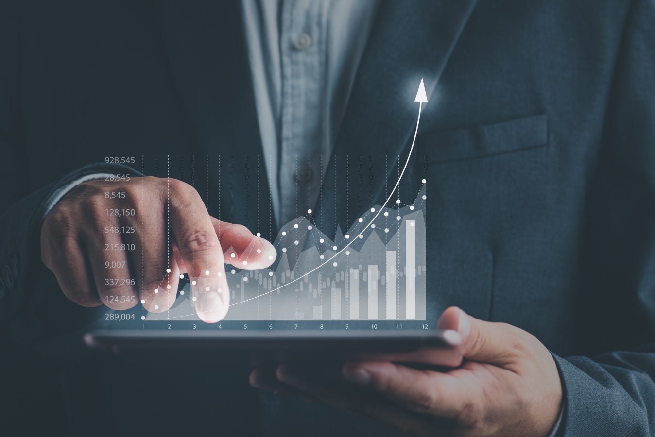 Businessman using tablet and using his finger to touch the screen with a business graph showing up in a virtual screen.